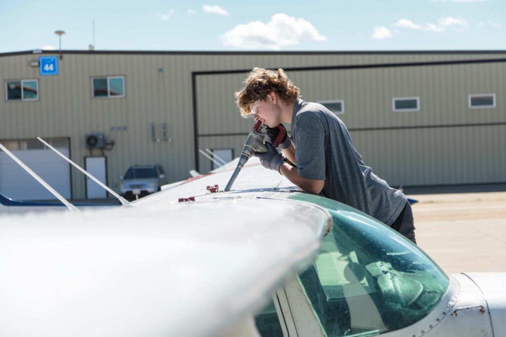 Young man cleaning the windshield of a small aircraft outside a hangar at Villeneuve Airport