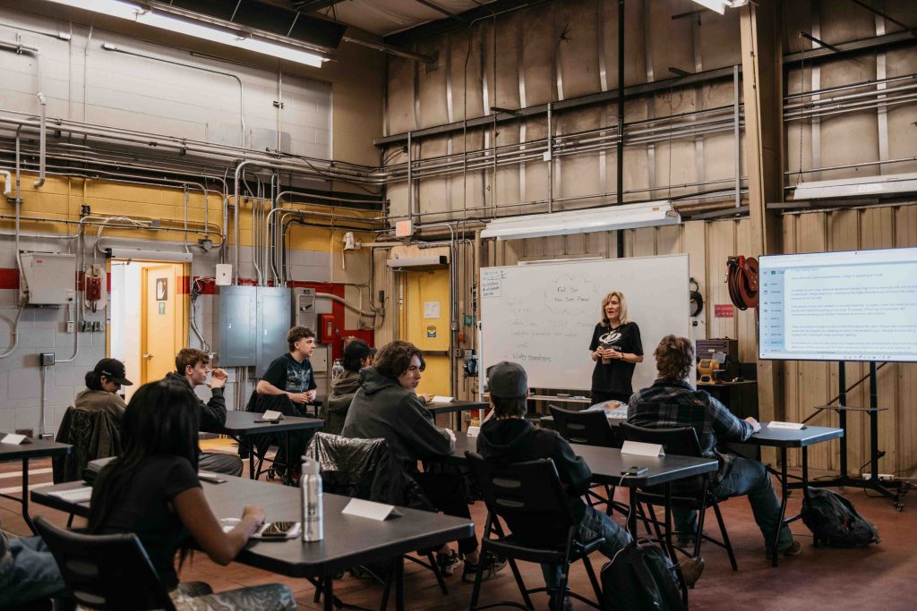 A woman instructor teaching a classroom of students in a hangar-style training room as part of the ZVL Aviation Pathway Program at Villeneuve Airport